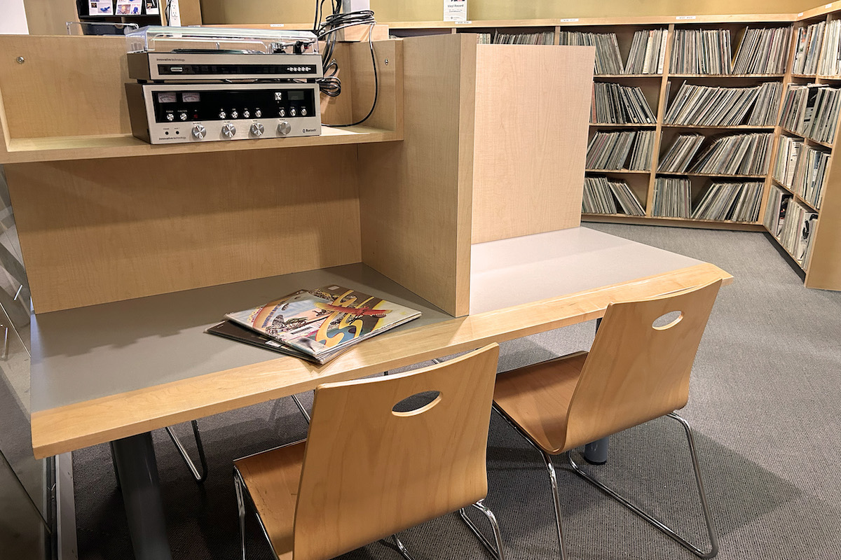 Study carrel with chairs and record player and listening equipment on shelf.